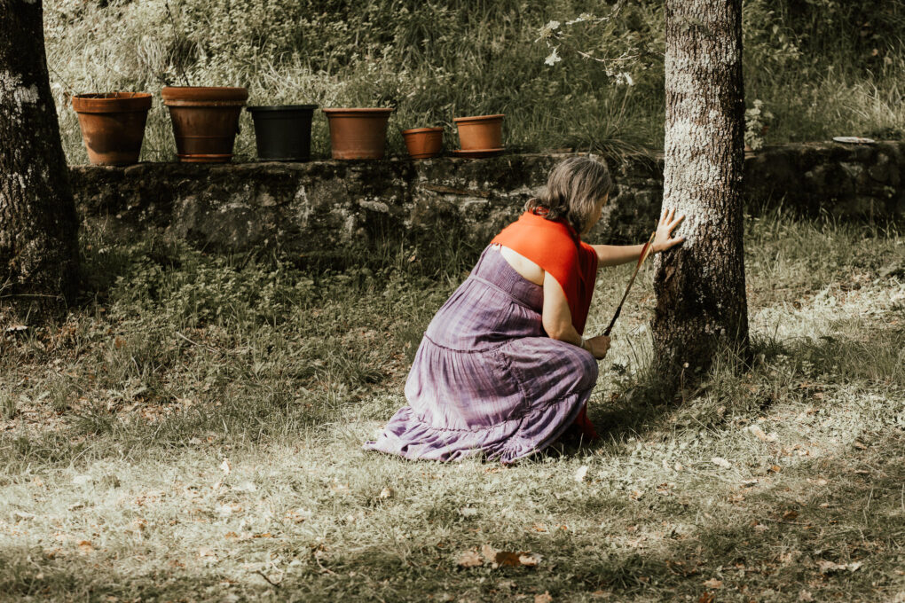 Donna accanto a un albero, immagine simbolica del lavoro sull’albero genealogico